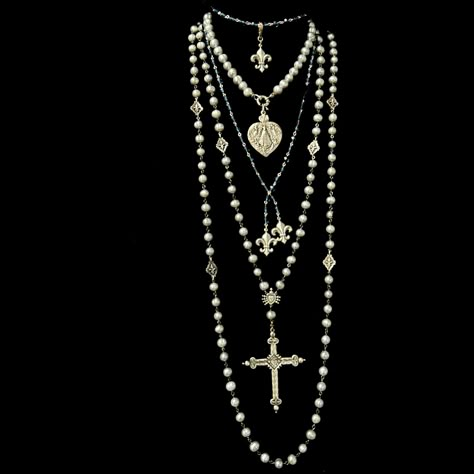 The Moonglow Sacred Heart Cross Rosary Necklace is designed as a true five decade rosary. It is 30" inches long and comes with a 4" complimentary extender that allows the necklace to be double. It features 9mm Silver Freshwater Pearls, mini Fleur de Lis and a reproduction French Sacred Heart Cross. The cross is two sided with the Sacred Heart on one side and a Lily at the center of the reverse. Length: 30" Gemstones: Silver Fresh Water Pearls Metal: Sterling Silver Clad Bronze Long Layered Pearl Necklace, Freshwater Pearls Jewelry, Silver Necklace Long, Necklace Silver Layered, Gothic Wedding Jewelry, Long Cross Necklace, Silver Long Necklace, Multiple Necklaces, Pearl Chains