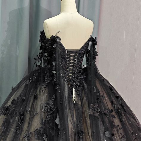 Timeless vintage-inspired Black Sweetheart Quinceanera Dress. Featuring an intricate beadwork bodice, off-the-shoulder long sleeves with a dramatic floral drape shoulder cape, this dress exudes glamour and luxury. The black lace overlay complete with hand sewn florals adds a touch of elegance, while the adjustable lace-up back ensures a perfect fit. Elevate your party look with this exquisite ball gown. material: glitter tulle, organza type: ball gown style: formals color as shown built in bra sweetheart neckline train as shown lace up back Black Dress Fairytale, Black Gowns Dresses Elegant, Black Quince Dresses With Sleeves, Black Quinceanera Dresses With Gold, Black And Silver Quinceanera Dresses, Black Ball Gown Elegant, Gothic Quinceanera, Black Sweet 16 Dresses, Black Masquerade Dress