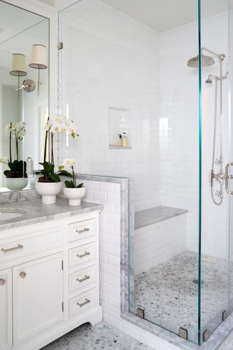 A glass-enclosed shower is fitted with a bench is this traditional master bathroom space. The potted flowers on the vanity are also seen in the kids' bathroom, adding continuity between the spaces. Minimalist Small Bathrooms, Makeover Kamar Mandi, Beautiful Master Bathrooms, Small Bathroom With Shower, Shower Bathroom, Bad Inspiration, Bathroom Curtain, Bathroom Shower Tile, Bathroom Remodel Shower