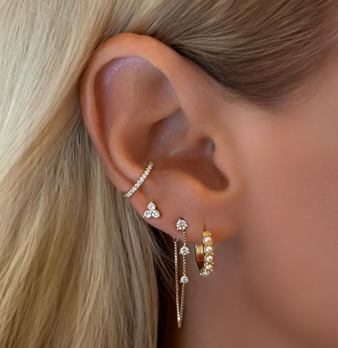 Tips For Curating the Perfect Dainty Feminine Ear Stack: There’s something magical about a well-curated ear stack—it’s like creating a miniature gallery on your ear. 1. Start with the Stud The foundation of any great ear stack is a chic and understated stud. Opt for something that speaks to your personal style—whether it’s a tiny diamond, a pearl, or a delicate gold ball. This piece anchors the look, adding a subtle sparkle that doesn’t overpower the rest of the stack. 2. Add a Huggie for... 3 Peircings Earring Stack, White Gold Earring Stack, Dainty Earring Stack, Ear Mapping, Miniature Gallery, Earring Huggies, Ear Piercing Combinations, Ear Stacking, Earring Stacks