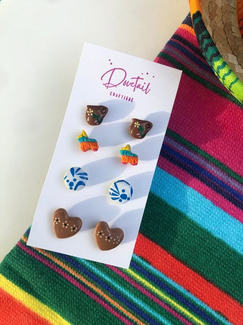 Looking for cute Latino-inspired polymer clay earrings? Grab this four-pack of mini studs that scream "Soy Latina!" Handmade here in the Alamo City, these Mexican-style stud earrings are perfect for a fiesta! You get all four flatback earring sets! This set includes glazed barro pottery jarritos, colorful fiesta piñatas (colors vary), glazed cazuelita style barro pottery heart studs, and classic talavera patterned round studs. Lightweight and colorful, these earrings are petite (see measurements) making them great for those looking for adorable interchangeable pairs or those with multiple piercings. They are also great for giving as a gift or sharing with a friend! Each set is secured to steel silver-toned posts with UV resin, making them long-lasting. All earrings are made of quality FIMO Mexican Clay Earrings, Frida Kahlo Party Decoration, Talavera Pattern, Unique Hair Bows, Pottery Heart, Diy Gifts To Sell, Mexican Earrings, Resin Making, The Alamo