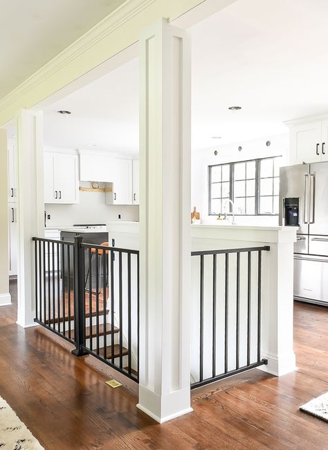 home with white craftsman style columns and black modern railing. #whitekitchen #ranchhome #rancher #craftsmancabinets #kitchendesign #openfloorplan #openconcept #openstairs Stairwell In Kitchen, Open Concept Kitchen Living Room With Basement Stairs, Remodel Open Floor Plan Before And After, Kitchen With Stairs In Middle, Ranch House Open Basement Stairs, Open Floor Plan With Stairs In Middle, Stairs Between Kitchen And Living Room, Small Ranch Renovation, Open Basement Stairs In Kitchen Half Walls