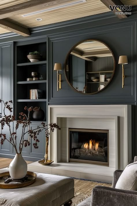 Elegant dark-themed fireplace with dark paneling, a white fireplace surround, a chic round mirror, and refined decor elements. Fireplace Panelling Ideas, Living Room With Brass Accents, Dark Living Room Fireplace, Wood Panel Walls Fireplace, Panelling Over Fireplace, Panelling Above Fireplace, Chimney Fireplace Ideas, Moody Living Room Fireplace, Fireplace Dark Wall