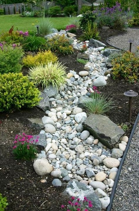 a beautiful and low maintenance garden incorporating a river rock dry stream with herbs and blooms around Stream Landscaping, Dry River Bed, Dry Stream, River Rock Garden, Dry Creek Bed, River Rock Landscaping, Dry River, Small Front Yard Landscaping, Rock Garden Design