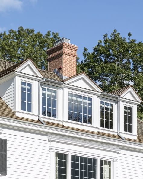 The renovated attic has a large dormer with three pedimented roofs. #brickchimney #cedarshingleroof #clapboardsiding #casementwindows #dormer #sheddormer #pedimenteddormers #colonialarchitecture #classicaldesign #traditionalarchitecture Adding Dormers To A House, Renovated Attic, Large Dormer, Dormer Addition, Dormer Ideas, Small House Renovation, Cape Cod House Exterior, Craftsman Remodel, Dormer Roof