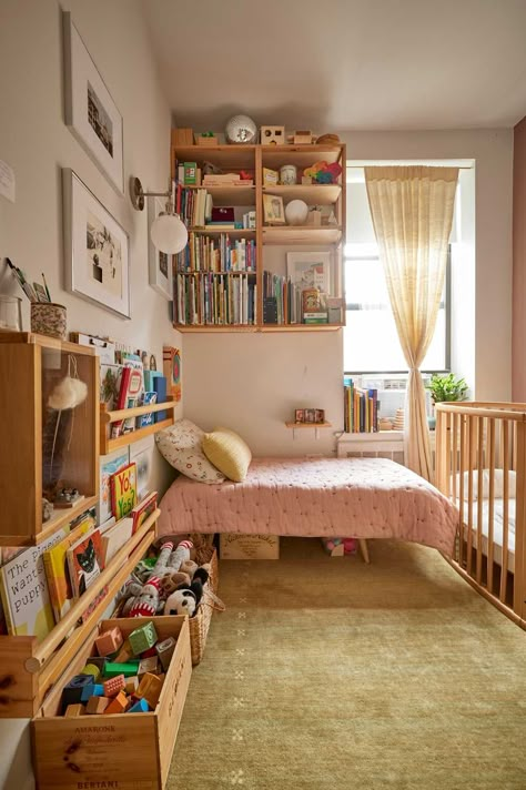 The wood shelving and book racks were made by Alex.  Credit: <a href="https://www.apartmenttherapy.com/authors/erin-derby">Erin Derby</a> Nursery Wood Floors, Girls Room Book Storage, Small Montessori Room, Small Bedroom And Playroom Combo, Kids Bedroom Bookshelf Ideas, Diy Toddler Bookshelf, Two Under Two Bedroom, 70s Playroom, Montessori Kids Bedroom