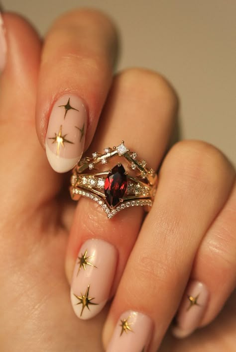 A woman's hand wearing a custom 3-piece wedding ring set from Staghead Designs. This 14K yellow gold ring set features an engagement ring with a marquise cut garnet center stone with claw prongs & round diamond accents & two contoured bands. The top band is V-shaped with princess cut diamonds that look celestial or like stars across the sky. The bottom band is V-shaped with pavé diamonds. This fully customizable set can also be made in 14K white or rose gold. Alternative To Engagement Rings, Game Of Thrones Engagement Ring, 3 Part Wedding Ring, Engagement Rings With Garnet, Raw Ruby Engagement Ring, Engagement Ring Unusual, Opal And Ruby Engagement Ring, Diamond Ring Styles, Persephone Engagement Ring