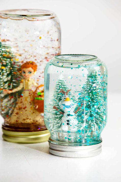 Making your own snow globe is easier than you think! Follow these simple instructions to create your own, DIY Snow Globe with the kids. #WelcometoNanas #DIYSnowGlobe #EasyCraftsforKids #SnowGlobewithGlue Snowglobe Jar Diy, Galaxy Snow Globe Diy, Diy Snow Globe Videos, Lighted Snow Globes Diy, Diy Crafts For Family, Mason Jar Snow Globes Diy, Diy Winter Snow Globe, Snow Globe Laminated Ornament, Holiday Art Projects For Preschoolers