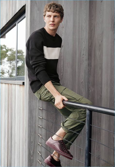 Embracing off-duty style, Tim Schuhmacher models a fine-knit sweater, cargo pants, and sneakers. Tim Schuhmacher, Simon Van Meervenne, Fine Knit Sweater, Another Round, Spring 2017, Off Duty, Cargo Pants, Military Jacket, Knit Sweater