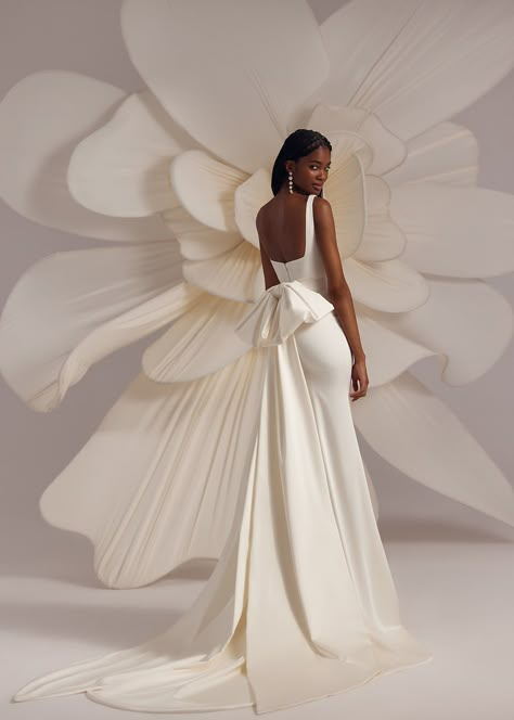 Bertie – strapped square neckline fitted dress with elongated skirt and a detachable wide ribbon bow on the back. Complemented with a transparent veil decorated with voluminous flowers on the edge. Dress With A Bow On The Back, Wedding Dresses With A Bow, Fitted Wedding Gown With Bow, Wedding Dresses With Bow On Back, 2025 Wedding Dress, Wedding Dress With Bow On Back, Dress With Bow In The Back, Modern Wedding Dress Minimalist, Wedding Dress With Big Bow