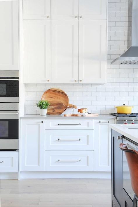 Polished nickel pulls accent white shaker kitchen cabinets topped with a gray quartz countertop complemented with white subway backsplash tiles completed with light gray grout. Kitchen Silver Handles, Nickel Kitchen Hardware, Handle Ideas, Top Kitchen Cabinets, White Shaker Kitchen Cabinets, Kitchen Handle, Grey Kitchen Island, White Shaker Kitchen, Kitchen 2024