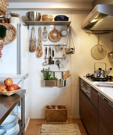 A narrow kitchen with dark cabinets and utensils hanging on metal rails and shelves on the end wall. Organiser Cucina, Kitchen Wall Storage, Narrow Kitchen, Small Kitchen Storage, Tiny Space, Dark Cabinets, Tiny Kitchen, Apartment Kitchen, Decoration Inspiration