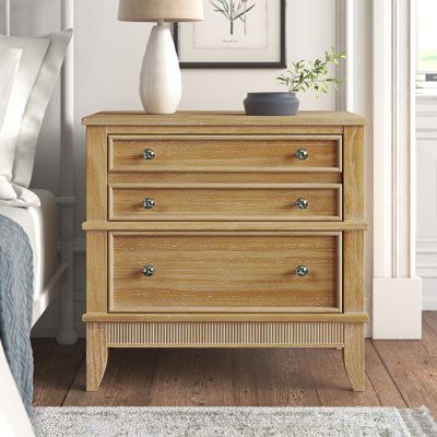 This 3-drawer nightstand is just what you need to keep your favorite reads and devices all within reach from your bed. It's made from solid pine wood, and has tapered legs and a slatted pattern on the bottom with a rustic natural wood finish for tons of French country charm. Three drawers with wooden inlays on the fronts glide open to hold essential items like reading glasses, hand lotions, and remotes. Plus, we love that the surface is perfect for holding a small lamp or a photo of friends and Nightstand Natural Wood, Wide Nightstands, Natural Oak Nightstand, Natural Wood Nightstand Farmhouse, Natural Wood 3 Drawer Nightstand, 3 Drawer Dresser Natural Wood, Light Wood Nightstand, Home Nyc, Kelly Clarkson Home