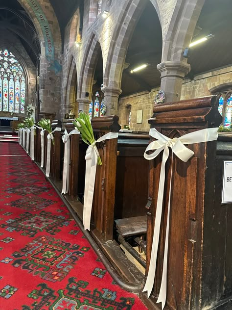 Fresh white tulip flowers and satin ribbon were the request of the bride to walk down the aisle for this beautiful village church wedding. Designed and installed by Cheryl Louise Venue: St James' Church, Staffordshire Aisle Bows For Wedding, Aisle Decorations Wedding Church, Church Aisle Wedding Decor, Small Chapel Wedding Decorations, Catholic Church Wedding Decorations, Church Pew Decorations Wedding, Church Wedding Ceremony Decorations, Church Aisle Decorations Wedding, Church Flowers Wedding