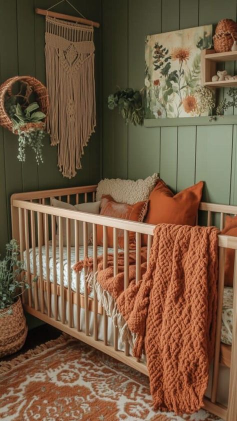 Green nursery with rust-colored accents, featuring macramé wall hanging, earthy textures, and cozy knit blankets. Neutral Colour Nursery Ideas, Nursery With Light Wood Crib, Green Woodsy Nursery, Fall Theme Nursery, Wooded Theme Nursery, Rust Colour Nursery, Nursery Light Green Walls, Peaceful Nursery Ideas, Sage Green Wall Nursery