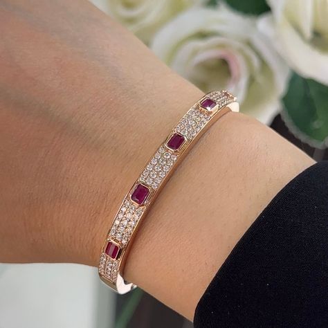 This bangle bracelet is a stunning testament to elegance and sophistication, crafted from lustrous 18 karat rose gold to exude warmth and charm. Adorning the bracelet are a mesmerizing array of natural diamonds and radiant emerald-cut rubies, creating a captivating contrast of sparkle and color. The bracelet features round-cut diamonds totaling 1.63 carats, boasting a remarkable G color and VS2 clarity. Set in a combination of pave and bezel settings, the diamonds shimmer with brilliance and fire, adding a touch of glamour to the design. Interspersed among the diamonds are enchanting emerald-cut rubies totaling 1.42 carats, set in bezel settings to accentuate their vibrant red hue. Their exquisite beauty adds a rich and captivating dimension to the bracelet, creating a striking harmony wit Ruby Bangles, Diamond Bangles, Diamond Bracelet Design, Ruby Bracelet, Diamond Bangles Bracelet, Bangles Jewelry Designs, Gold Jewelry Indian, Bangle Designs, Jewelry Lookbook