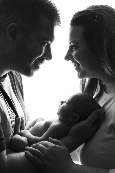 black and white image of Mum and Dad holding newborn baby girl and smiling at eachother First Time Family Photos, New Born Parents Pictures, Couples Newborn Photoshoot, Baby Photo Shoot With Parents, Baby Photo With Parents, Family Portrait Newborn, Black And White Newborn Family Pictures, Studio Newborn Parent Poses, Black And White Newborn Photos