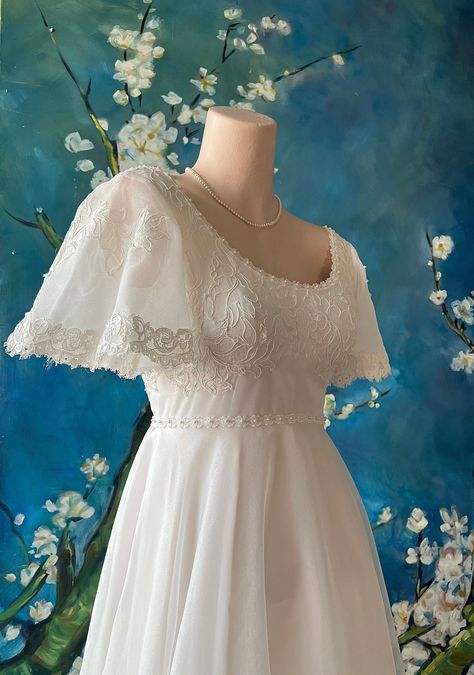 Romantic Regency 1950s Chantilly lace wedding gown with Jane Austen vibes and Edwardian style back bustle with a delicate bodice, tiny white satin ribbon bows at sleeve and back . A sweet scalloped lace at neck, frames the decolletage so softly. A little piped edge runs around the high waist for added interest. Tiny mini pearl beads are attached at bodice front and sleeves. There is lace that runs along the edge of the full lace skirt and train that creates a bustle effect at the back, almost an Edwardian inspired style. The under dress has turned an off white that accents the white lace beautifully. Metal zipper closure at back with an under slip netting at bustle for just the right fullness. This fabulous dress has been professionally cleaned and is in near MINT condition for its age! Th Wedding Dress Sleeve Types, Sleeves Ideas For Dress, Vintage Wedding Dress Long Train, 19th Century Inspired Wedding Dress, Flutter Sleeves Dress, Wedding Dresses Satin Modest, Wrist Loop Wedding Dress, Regency White Dress, Broderie Anglaise Wedding Dress