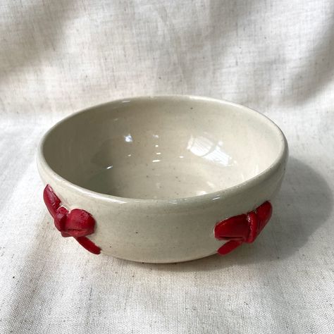 Cute bow bowl 🎀 #pottery #potteryart #bow #bowl #clay #claybowl #claybows #redandwhite #🎀 #stoneware #ceramics #cuteceramics #ceramicart #ceramicsofinstagram #pottersofinstagram #tending #aesthetic #new Christmas Ceramics Bowl, Small Pottery Bowl, Small Ceramic Bowl Ideas, Clay Bowls Aesthetic, Aesthetic Clay Bowl, Pinch Bowls Ideas, How To Make A Bowl Out Of Clay, Bowl Clay Ideas, Ceramic Yarn Bowl Ideas