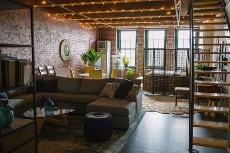 This brick industrial loft is full of plants and pops of yellow. We love the iron accents, the wooden stairs and the string lights on the ceiling. Brick Apartment, Industrial Apartment, Artist Loft, Brick Loft, Loft Interiors, Living Room Photos, Apartment Aesthetic, Loft Design, Industrial Loft