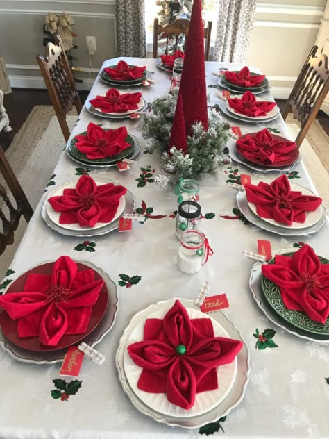 Setting the Christmas table can be as easy as folding your napkins into poinsettia flowers. And they’re easy to make! Crafts Using Cloth Napkins, Best Christmas Table Decorations, Napkin Cloth Folding, Christmas Napkin Decorations, How To Fold Dinner Napkins Holidays, Napkin Folding For Christmas Table, Christmas Tree Folded Napkins, Pointsetta Christmas Decor, Christmas Cloth Napkin Folding Ideas