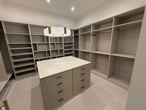 Spacious neutral color walk-in closet with island. Walk-in Closet Island Ideas, His And Hers Walk In Closet Design, Corner Walk In Closet, Walk In Closet With Island, Big Walk In Closet, Closet With Island, Closet Island, A Walk In Closet, Dream Closet Design