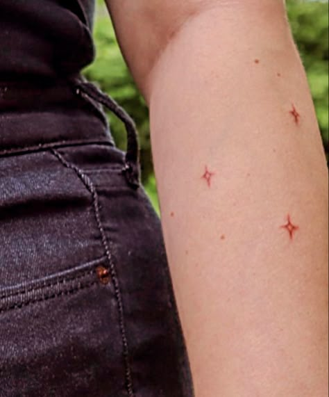 3 stars tattooed on arm Brown Ink Star Tattoo, Red Ink Star Tattoo, Sparkle Freckle Tattoo, Brown Star Tattoo, Red Stars Tattoo, Red Sparkle Tattoo, Galaxy Shoulder Tattoo, Star Tattoo Color, Red Tiny Tattoo