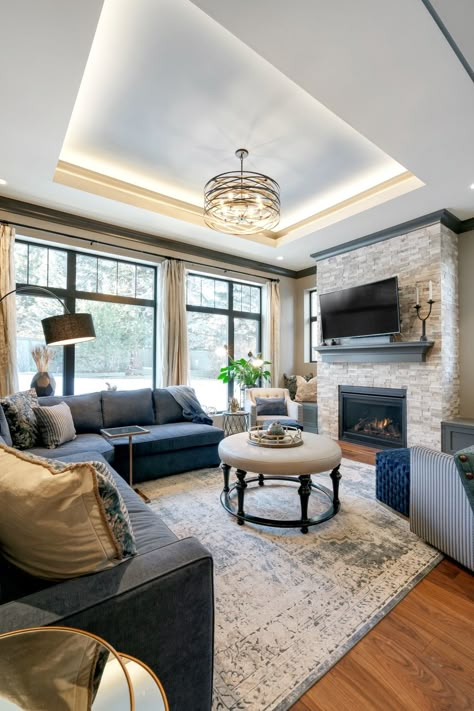 A home addition that added an sunroom/living room off of the kitchen a dining room. This new living room features large windows, walnut floors, a stone fireplace, custom built-ins and tray ceiling.  Built in the community of Coach Hill in Calgary, AB. www.melansonhomes.com | info@melansonhomes.com | 403-690-1000 13ft Ceiling Living Room, Living Room With Tray Ceiling, Elevated Ceiling Living Rooms, Statement Ceiling Living Room, Built In Ceiling Lights, Living Room Designs Large Windows, Fireplace With Tray Ceiling, Living Rooms With Windows, Living Room Windows Large