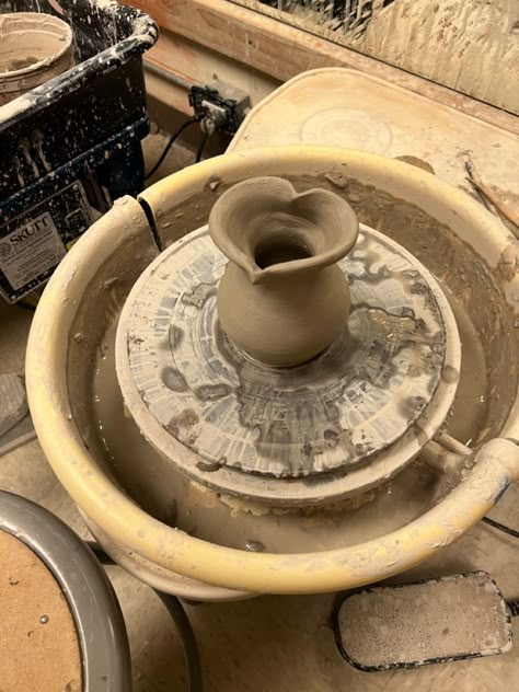 an unfired heart shaped vase made from clay sitting on a potter’s wheel. Potter Aesthetic Clay, Wheel Thrown Pottery Forms, Pottery Throwing Aesthetic, Ceramic Vase Wheel Thrown, Ceramics Class Aesthetic, Pottery Asthetic Ideas, Wheel Projects Pottery, Simple Wheel Thrown Pottery, Ceramics Wheel Ideas