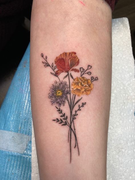 Tattoo of an aster, a poppy, and a marigold on forearm Aster And Cosmos Flower Tattoo, Aster And Cosmos Tattoo, Poppy Marigold Tattoo, Marigold Rose Tattoo, Poppy And Aster Tattoo, Poppy And Marigold Tattoo, Autumn Flower Tattoo, Daisy Rose And Marigold Tattoo, Poppy And Aster Flower Tattoo