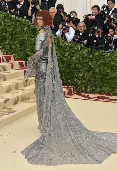 Theme = “Heavenly Bodies: Fashion & the Catholic Imagination” | Zendaya, 21, wore a ‘Versace’ dress that looked like a knight's armor w/ even metal shoulder pads & chains, plus a back peephole & a gorgeous chain-link train, which looked heavy to haul up those steps. She paired it w/ matching ‘Jimmy Choo’ heels & ‘Tiffany & Co.’ jewelry. Astoundingly like the paintings of Joan of Arc, even the red hair/simple makeup look. In awe of her overall look | Photo: Getty/Neilson Barnard Zendaya Armor Dress, Met Gala Aesthetic, Gala Aesthetic, Zendaya Met Gala, Rihanna Dress, Law Roach, Mood Bored, Gala Gowns, Gala Gown