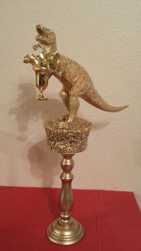 DIY trophy made from Dollar Tree items: a piece of Styrofoam, a toy dinosaur and a party favor plus a candlestick from the thrift store all hot glued together & sprayed with gold paint. Homemade Trophies, Funny Trophies, Diy Trophy, Fantasy Football Gifts, Funny Baby Shower Games, Minute To Win, Thrift Store Crafts, Minute To Win It, Halloween Party Diy