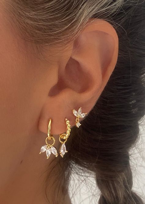 Introducing our exquisite gold-toned marquise earrings—a harmonious blend of classic charm and modern elegance. The earrings feature a delicate petal-like arrangement, reminiscent of a flower or leaf. Pair with Single clear drop earrings and marquise stud earrings for your stunning ear stacks. A. Hannah Dangle• Material: 18k Gold Plated on 925 sterling silver, AAAAA Cubic Zirconia• Size: Charm size: 11mm, Hoop inner diameter: 9mm B. Single Clear • Material: 18k Gold Plated on 925 sterling silver Gold Ear Designs, Gold Formal Earrings, Gold Earring Inspiration, Earring Stack Gold, Gold And Silver Earrings Mixing, Second Ear Piercing Ideas, Stacked Ear Piercings, Earring Stacks Gold, Cute Piercing Ideas