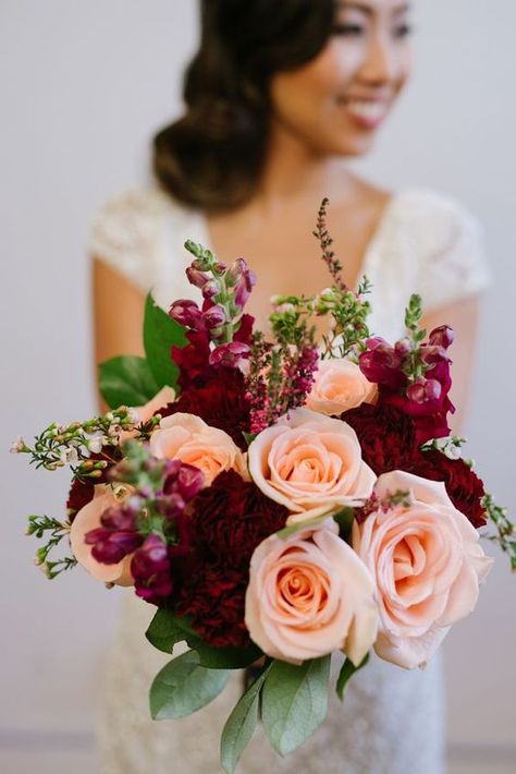 Burgundy and peach for burgundy wedding colors for 2025, burgundy bridesmaid dresses, white bridal gown, navy blue bridegroom suit and peach flower boutonniere, burgundy and peach flower and greenery bouquets, centerpieces and wedding cake décor, burgundy wedding napkins. Peach Floral Arrangements, Wedding Colors 2025, Boutonniere Burgundy, Bridesmaid Dresses Burgundy, Greenery Bouquets, Colors 2025, Bridesmaid Dresses White, Burgundy Wedding Colors, Peach Bridesmaid Dresses