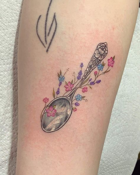 Tattoo of a decorative silver spoon with a thin green vine wrapped around. The vine has small green leafs interspersed with blue, pink and purple flowers. Small Spoon Tattoo Ideas, Apron Tattoo Ideas, Silver Spoon Tattoo, Antique Spoon Tattoo, Small Spoon Tattoo, Disabled Tattoo, Teaspoon Tattoo, Remy Drawing, Dysautonomia Tattoo