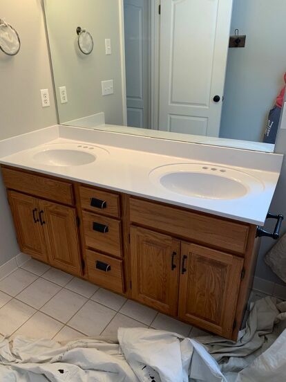 My builder grade Master Bathroom vanity was bad. Really bad. After two years I finally decided to do something about it and got to work. Here’s a before photo of the bathroom. Break Out the Spray Cans I used a can of Rustoleum Matte Black spray paint I had in the basement on the light fixture for a quick, easy and free light refresh! Cover Everything! For the countertop I purchased a $4.00 can of Rustoleum Appliance Epoxy spray paint from Walmart. I heard it produced lots of overs… Spray Paint Light Fixture Black, Rustoleum Appliance Epoxy Spray On Countertops, Epoxy Spray Paint Countertop, Master Bath Black Vanity, Rustoleum Appliance Epoxy, Bathrooms With Black Vanities, Bathroom Black Cabinets, Black Bathroom Cabinet, Appliance Epoxy