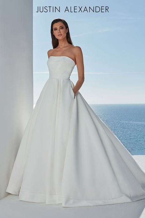 This satin ball gown is elevated and uncomplicated. Designed with a straight neckline accented with horizontal seaming that compliments the box pleats in the skirt. Detailed with pockets, a satin hem, and buttons to the end of the train. Justin Alexander Dress, Plus Size Ball Gown, Justin Alexander Bridal, Justin Alexander Wedding Dress, Satin Ball Gown, Lillian West, Bridal Elegance, Justin Alexander, Wedding Dress Pictures