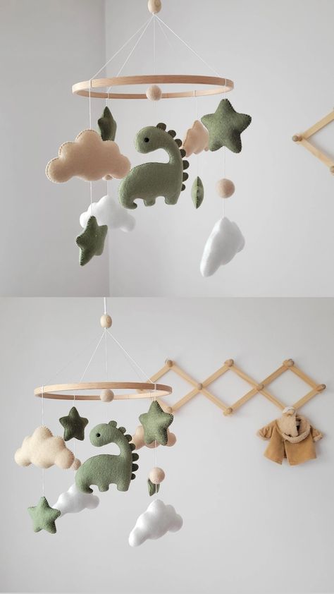 Adorable felt baby mobile featuring a charming green dinosaur. 💚

This baby mobile is meticulously handmade with attention to detail, ensuring a high-quality and delightful addition to your nursery decor. It is crafted using safe and eco-friendly materials, making it a perfect choice for your little one. 🌿 Nursery Decor Dinosaur, Sage Dinosaur Nursery, Simple Dinosaur Nursery, Cute Dinosaur Nursery, Dinosaur Mobile Diy, Baby Nursery Dinosaur Theme, Dinosaur Theme Nursery For Boys, Green Dino Nursery, Dinasour Themed Nursery