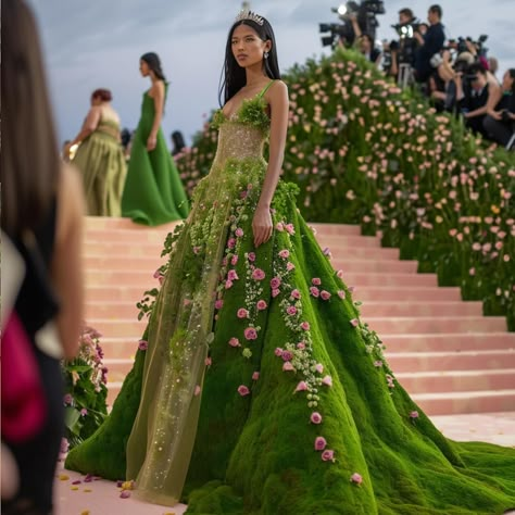 If the Met Gala participants had truly embraced the theme of ‘Garden of Time’, this is what they could have looked like!! Amidst cascading floral arches and verdant pathways, celebrities are adorned in attire that transcends mere fashion; it’s an ode to the passage of time itself. Picture breathtaking gowns adorned with delicate, shimmering clockwork motifs, where intricate gears replace traditional embroidery. Celebrities don headdresses resembling blooming timepieces, where each petal and g... Met Gala Flower Dress, The Garden Of Time Fashion, Garden Of Time Dress Met Gala, Met Gala Garden Of Time, Met Gala Wedding Theme, Garden Of Time Met Gala, Green Couture Gown, Garden Of Time Dress, Met Gala Dresses Gowns