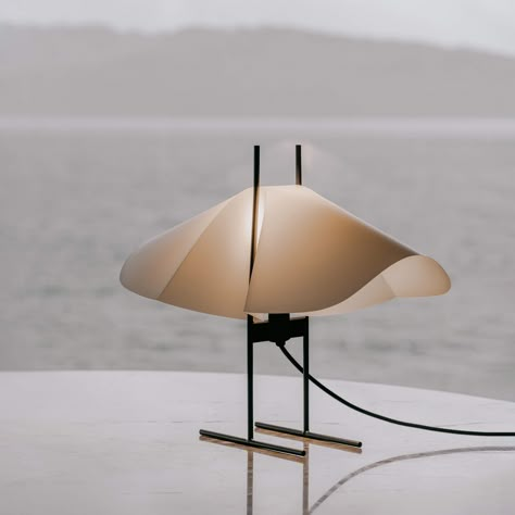 CHO lamps are the result of a study on shapes that appear when adding pressure to an oval piece of paper. A sheet with two curved pressings, gently wedged into a slim metal frame. As a wing catch carrying itself resiliently between two pylons. Here it unfolds into a poetic shade that spurs on creative interpretation of the beholder and changes at the point of view. Cho means butterfly in Japanese which is how the shape speaks to the designers. The lightness of the shade meeting the solidity of t Curved Product Design, Butterfly In Japanese, Japanese Product Design, Metal Lamp Design, Product Design Ideas, Midcentury Lamp, Paper Lamp Shade, Study Table Lamp, A Wing