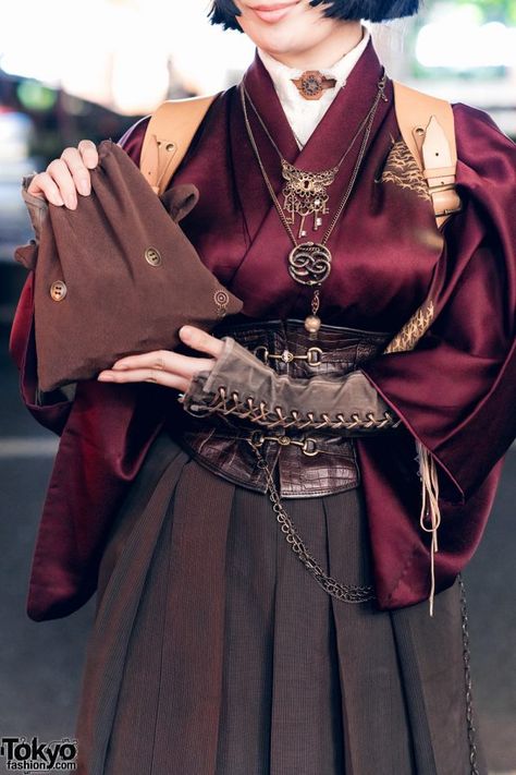 "On the left is Liz, a shoemaking student wearing her grandmother’s maroon silk kimono. She wore it with a white high-necked top and a dark brown hakama skirt, which were cinched with a dark brown leather corset from Excentrique and a harness from Hazy Moon Steamory. Peaking out from her kimono are brown-gray long sleeves with lace-up details. Her accessories include a handmade bag and chain necklaces with large pendants. A pair of black leather boots with high block heels and a black bob..." Steampunk Clothes, Kimono Styles, Solar Punk, Gown Fashion, Fantasy Stuff, Mode Chanel, Medieval Clothing, Character Inspo, Tokyo Fashion