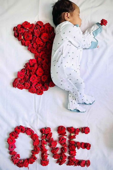 A baby laying on a bed with red roses arranged in the shape of a wing. 1 Months Baby Photoshoot Ideas, Months Photos Baby Ideas, Monthly Baby Photos Girly, Rose Maternity Shoot, Newborn Monthly Pictures Photo Ideas, Baby 100 Days Photo Ideas, Photo Shoot Ideas For Baby, February Baby Photoshoot, Newborn Baby Shoot Ideas