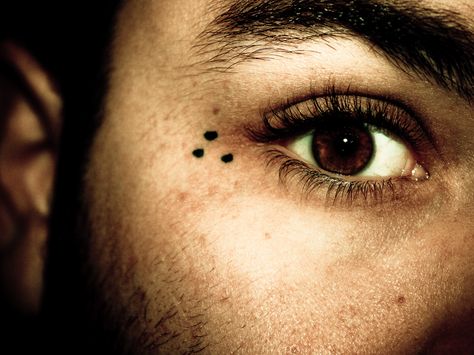 The three dots tattoo is a very common prison tattoo that symbolizes 'mi vida loca' or 'my crazy life.' It doesn't symbolize any particular gang, but rather the gang lifestyle. It's typically found on the hands or around the eyes. Three Dots Tattoo Meaning, Prison Tattoo Meanings, Dot Tattoo Meaning, Dotted Tattoo, 3 Dot Tattoo, Under Eye Tattoo, Tattoo On Face, Triangle Tattoo Meaning, Eye Tattoo Meaning