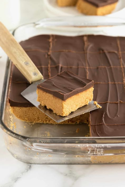 A no-bake chocolate peanut butter bar on a metal spatula with a wooden handle in front of a baking dish of chocolate peanut butter bars. Peanut Butter Snacks Easy, Chocolate Peanut Butter Squares, Butter Bars Recipe, Butter Squares, Peanut Butter Bar, Peanut Butter Oat Bars, Chocolate Peanut Butter Bars, Peanut Butter Cookie Bars, Peanut Butter Squares