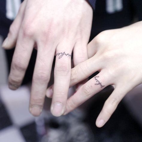 Wedding Ring Tattoos: Name Ring Tattoo. A cursive name inked where a traditional ring would sit. Click through for 30 wedding ring tattoo ideas. #weddingringtattoos #ringtattoos #weddingideas IG: @minsong.ttt Ring Finger Tattoos For Couples, Husband And Wife Ring Finger Tattoos, Married Ring Tattoos, Ring Couple Tattoos, Wedding Finger Tattoo For Men, Tattoo On Wedding Finger, Name On Finger Tattoos For Women, Name Tattoo On Finger For Women, Mini Finger Tattoos For Women