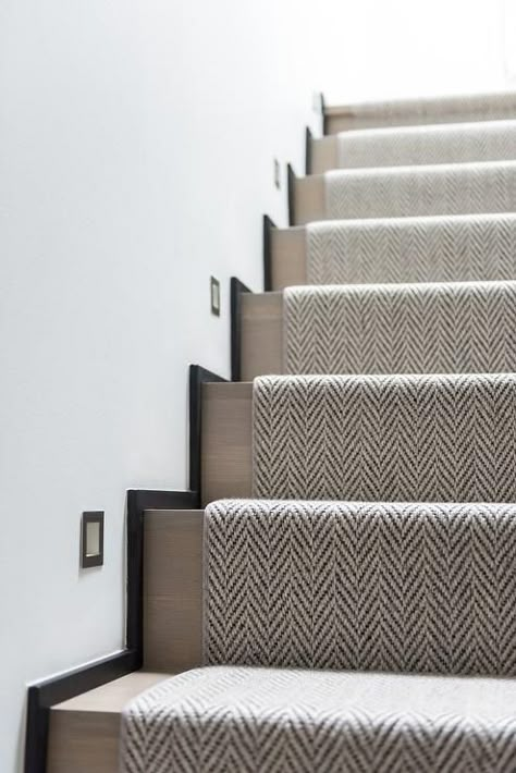 A woven herringbone rug accents a gray wash staircase illuminated by inset lights. Carpeted Stairs, Stairs Lighting, Herringbone Rug, Carpet Staircase, Staircase Runner, Staircase Remodel, Hallway Designs, Runner Carpet, Entrance Foyer