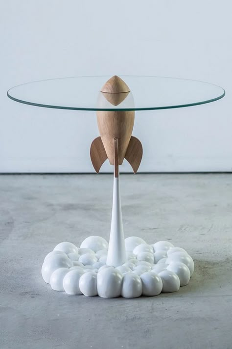 This cool new Rocket Table from the Mousarris Design Studio depicts a retro-futuristic sci-fi rocket ship blasting off into space with a glass tabletop riding on its nosecone and a puffy smoke trail exhaust doubling as its base. Space Themed Interior Design, Retro Space Decor, Sci Fi Decor, Space Ships Design, Scifi Furniture, Sci Fi Furniture, Futuristic Decoration, Futuristic Table, Spaceship Decor