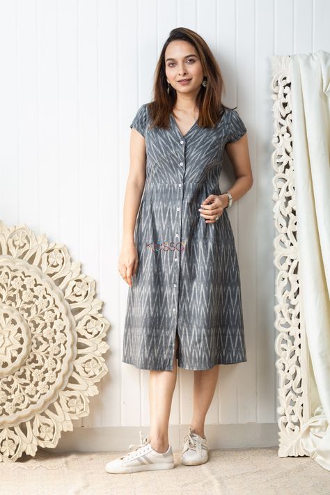 Cut in a distinct mid length A-line silhouette, the ikat grey mid-length dress is carefully handwoven with a dainty ikat pattern in grey and white tones. A great choice for daily-wear, this soft cotton outfit is embellished with front buttons, side pleats and V-neck. The dress comes with two side pockets. Daily Wear Kurtas Cotton, Ikat One Piece Dress, Cotton Daily Wear Dresses, Front Button Frock Design, Cotton A Line Frocks For Women, Ikat Cotton Dress, Simple Daily Wear Kurti Design, Cotton Ikat Dress, Aline Cotton Dress