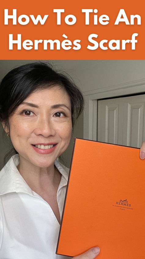 asian woman over 50 holding orange Hermes scarf box. Diy Silk Scarf How To Make, How To Tie Hermes Silk Scarf, How To Tie An Hermes Scarf, How To Tie A French Scarf, Scarf On Purse How To, How To Tie A Square Knot Scarf, Tie Hermes Scarf, How To Wear An Hermes Scarf, Hermes Scarves How To Wear