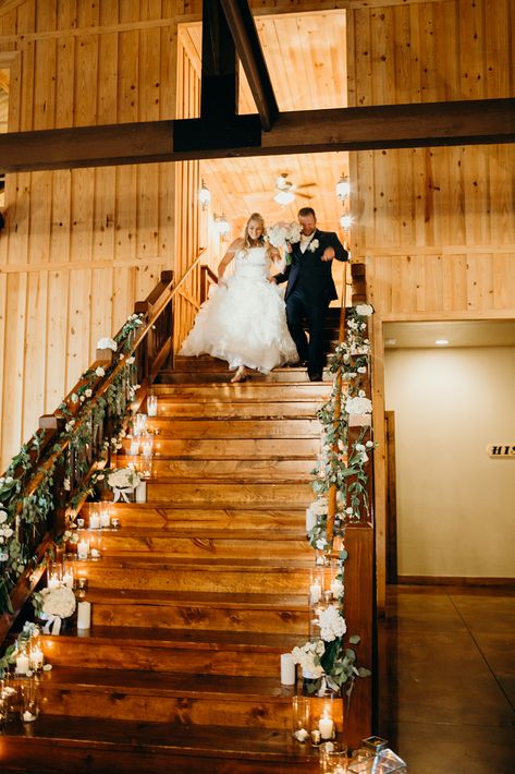 | elegant wedding reception entrance | elegant wedding reception staircase decor with candles + greenery | brides of oklahoma | tulsa wedding venue | oklahoma wedding venue | candid bride + groom photos | wedding day moments | photo taken at THE SPRINGS Event Venue. follow this pin to our website for more information, or to book your free tour! SPRINGS location: Tulsa, OK photographer: Watson & Payne #brideandgroom #weddingreception #weddingdecor #weddingphotos #weddingdecorations #bridesofok Wedding Venue Staircase Decor, Wedding Staircase Decoration Railings, Wedding Grand Staircase, Indoor Riding Arena Wedding, Wedding Entrance On Horse, Bride Coming Down Stairs, Wedding Stairs, Tulsa Wedding Venues, Wedding Reception Entrance